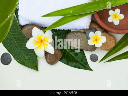 Spa or wellness background with white towels, tropical leaves, flowers and stones. Stock Photo