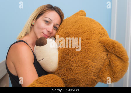 Portrait of a beautiful woman hugging her Teddy bear Stock Photo