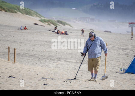 Old man treasure hunter or prospector using a metal detector seeking for lost objects Pacific City beach, Cape Kiwanda, Oregon coast, USA. Stock Photo