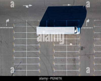 Long shadows from truck on a parking lot for cars with numbered seats in a sunny day. Stock Photo