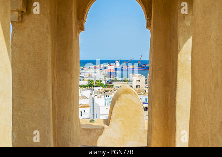 The small window in tower of Ribat fortress overlooks the roofs of Medina and industrial port, Sousse, Tunisia. Stock Photo