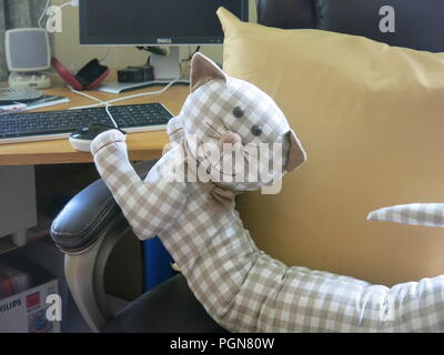 Stuffed toy cat has captured a mouse, her paw is on the computer mouse; an IT literate feline. Stock Photo
