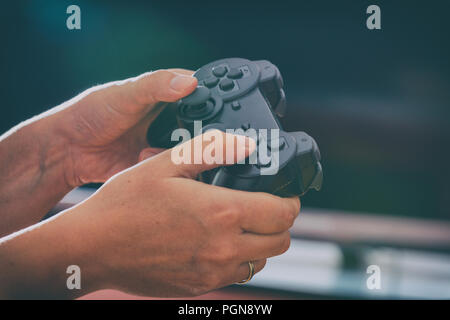 Mature woman or wife plays video game using the gamepad at home Stock Photo