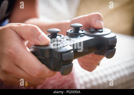 Mature woman or wife plays video game using the gamepad at home Stock Photo