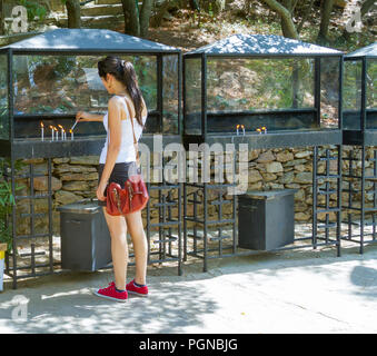 Young woman lighting prayer candles Stock Photo