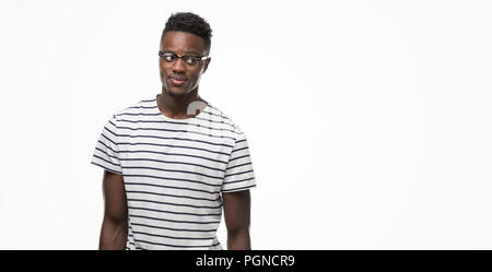 Young african american man wearing glasses and navy t-shirt smiling looking side and staring away thinking.
