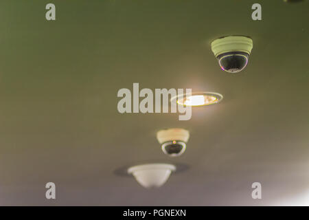 View of CCTV security digital camera on ceiling with lighting lamp to monitor and protection system. Stock Photo