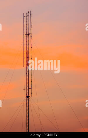 Cellular transmitter, folded dipole radio antenna for telecommunications with colorful sky background. Silhouette amateur radio antenna tower in drama Stock Photo