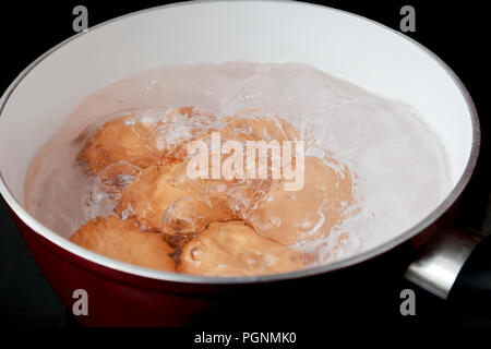 Six eggs boiling in a saucepan on an Induction Hob Stock Photo