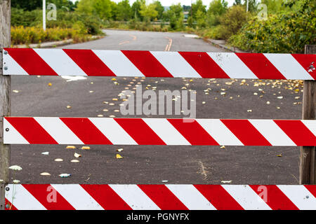 Road block barricade sign stripes white and red with road behind Stock Photo