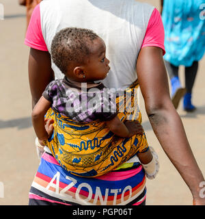 KUMASI, GHANA - JAN 15, 2017: Unidentified Ghanaian little girl is carried by her mother at the Kumasi market. Ghana children suffer of poverty due to Stock Photo