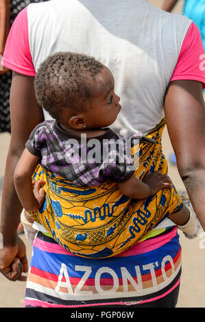 KUMASI, GHANA - JAN 15, 2017: Unidentified Ghanaian little girl is carried by her mother at the Kumasi market. Ghana children suffer of poverty due to Stock Photo