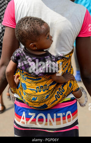 KUMASI, GHANA - JAN 15, 2017: Unidentified Ghanaian little girl is carried by her mother at the Kumasi market. Ghana children suffer of poverty due to Stock Photo