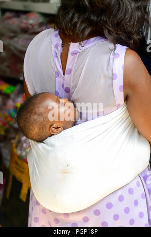 KUMASI, GHANA - JAN 15, 2017: Unidentified Ghanaian little baby is carried by his mother at the Kumasi market. Ghana children suffer of poverty due to Stock Photo