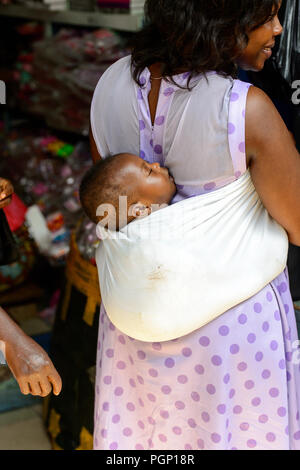 KUMASI, GHANA - JAN 15, 2017: Unidentified Ghanaian little baby is carried by his mother at the Kumasi market. Ghana children suffer of poverty due to Stock Photo