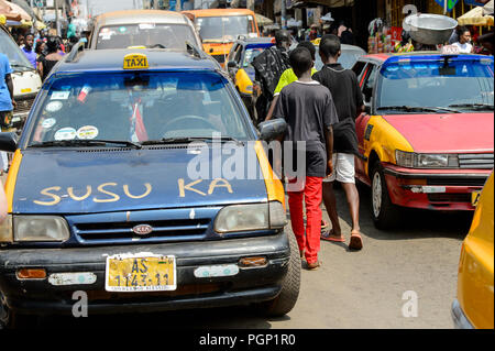 KUMASI, GHANA - JAN 15, 2017: Unidentified Ghanaian boys walk among the cars at the Kumasi market. Ghana children suffer of poverty due to the bad eco Stock Photo