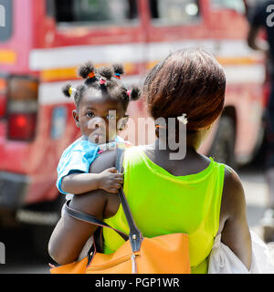 KUMASI, GHANA - JAN 15, 2017: Unidentified Ghanaian baby girl is carried by her mother at the Kumasi market. Ghana children suffer of poverty due to t Stock Photo