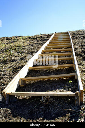 A clumsy wooden ladder lying on an earthen hill. Conceptual-movement up steep inconvenient steps, business, creativity, human development Stock Photo