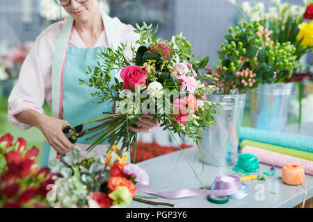 Crop view of smiling woman arranging flower bouquet in shop Stock Photo