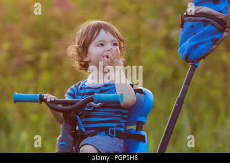 cute baby boy with bike in sunset light Stock Photo