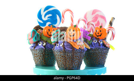 Happy Halloween candyland drip cake style cupcakes with lollipops and candy on white background. Stock Photo