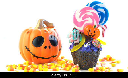 Happy Halloween candyland drip cake style cupcakes with lollipops and candy on white background. Stock Photo