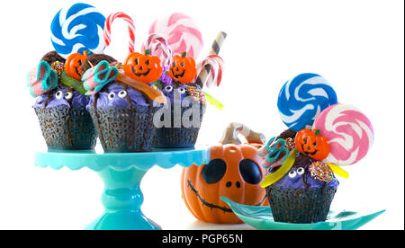 Happy Halloween candyland drip cake style cupcakes with lollipops and candy on white background. Stock Photo