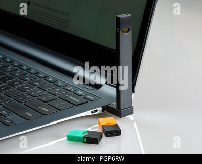 Juul nicotine vapor dispenser charging in USB charger Stock Photo