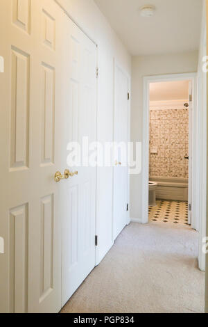 Hallway leading to bathroom of small condominium unit painted in white - USA Stock Photo