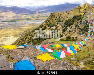 wind wavering Buddhist Tibetan Chinese prayer flags with Sanskrit calligraphy written decorating mountain valley in Tibet, China, Asia. Belief, Faith, Stock Photo