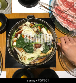 Japanese nabemono hotpot dish of thinly sliced meat and vegetable boiled in water served with dipping sauces, also known as Shabu-shabu. The food is c Stock Photo