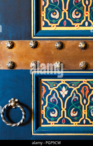 Moroccan close up detail of a painted door with hardware. Great example of Moroccan style and design. Rich blue background with floral panel inset. Stock Photo