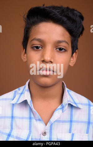 Young Indian boy wearing checkered shirt against brown backgroun Stock Photo