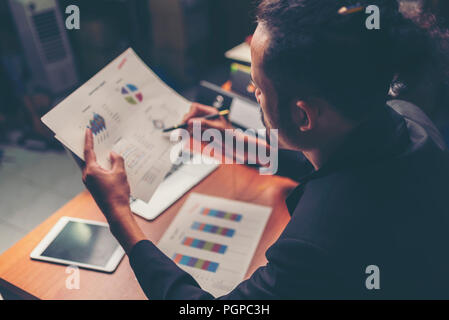 Businessmen are analyzed data from report using smartphone and laptop computer. Stock Photo