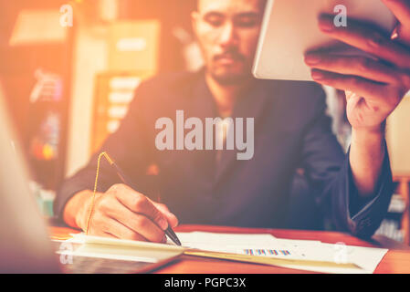 Businessmen are analyzed data from report using smartphone and laptop computer. Stock Photo