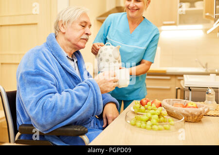 Senior man gets breakfast in the kitchen from a nursing wife Stock Photo