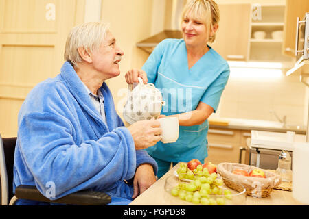 Senior man and caregiver having breakfast with coffee pot in assisted living Stock Photo