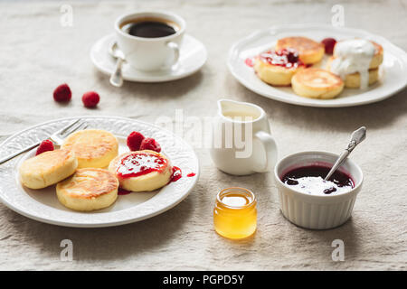 Breakfast Table With Curd Fritters or Pancakes, Coffee, Jam and Honey. Russian, Ukrainian cuisine. Cozy breakfast or comfort food concept Stock Photo