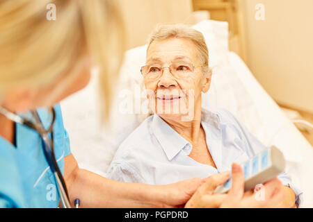 Nursing service cares for a bedridden senior woman in the hospital bed in the nursing home Stock Photo