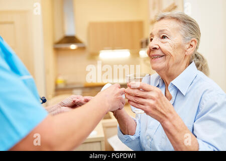 Senior as a patient receives medicine from nursing wife in assisted living Stock Photo
