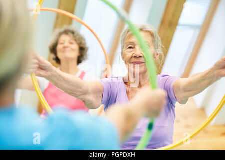 Seniors do gymnastics with hoops in a physiotherapy rehab course Stock Photo