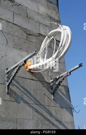 Flexible pipes with thermal insulation hang on the wall of a modern building. A new air conditioner will be installed here. Stock Photo