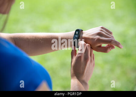 Modern sport gadget concept - young woman using a smartband and monitoring her workout in close-up (mixed). Stock Photo