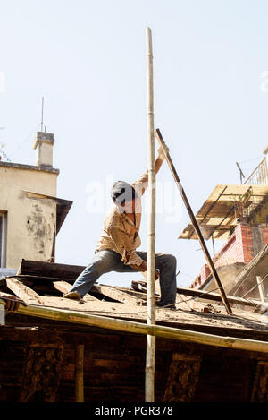 KATMANDU, NEPAL - MAR 6, 2017: Unidentified Chhetri boy repairs the roof. Chhetris is the most populous ethnic group of Nepal Stock Photo