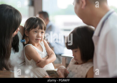 Candid shoot of people in cafeteria. Little girl with various face expression. Asian family outdoor lifestyle with natural light. Stock Photo