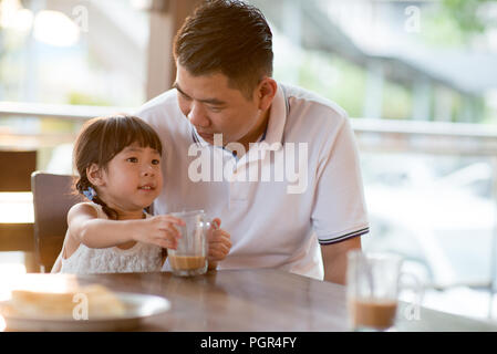 Little child drinking chocolate at cafe. Asian family outdoor lifestyle with natural light. Stock Photo