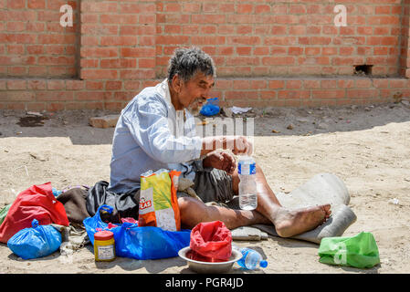 KATMANDU, NEPAL - MAR 6, 2017: Unidentified Chhetri grey-haired man sits on the ground and holds a plastic bottle with water. Chhetris is the most pop Stock Photo