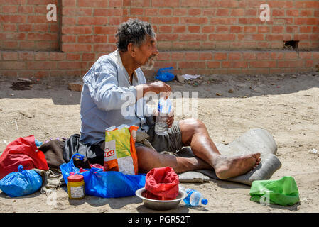 KATMANDU, NEPAL - MAR 6, 2017: Unidentified Chhetri grey-haired man sits on the ground and holds a plastic bottle with water. Chhetris is the most pop Stock Photo