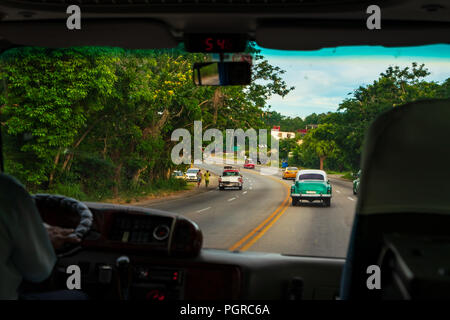 Looking through car window to road, wonderful view of old cars typical of Cuba and a moment of real life. Stock Photo