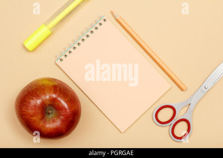 School supplies. Apple, felt pen, notebook, color pencil and scissors on beige background. Top view with copy space. Back to school concept. Pastel co Stock Photo